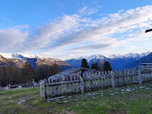 A mountainous landscape with a wooden fence and a small building.