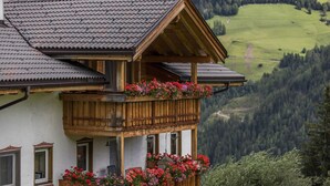 A chalet with a balcony, wooden beams, and a mountainous backdrop. - Vacation Apartment "Golserhof Sonne" in the Ahrntal Valley with Mountain View (Steinhaus Ahrntal)