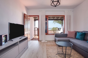Una sala de estar moderna con televisor de pantalla plana, un sofá, una mesa de centro y un balcón con vistas.