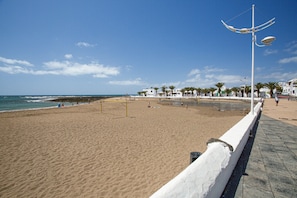 Una playa con una cerca blanca, un arco de fútbol y palmeras.