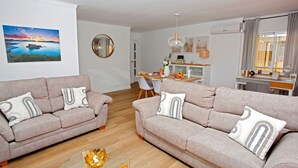 Un salon moderne avec deux canapés, un coin repas et une cuisine en arrière-plan.