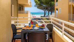 Un balcon avec une table préparée pour le petit-déjeuner, donnant sur une plage et la mer.
