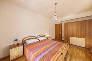 Une chambre à coucher avec un lit en bois, une table de chevet, une lampe, une armoire et un ventilateur de plafond.