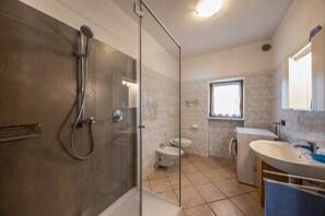 Une salle de bain moderne avec une douche à parois de verre, des toilettes, un lave-linge et un lavabo.