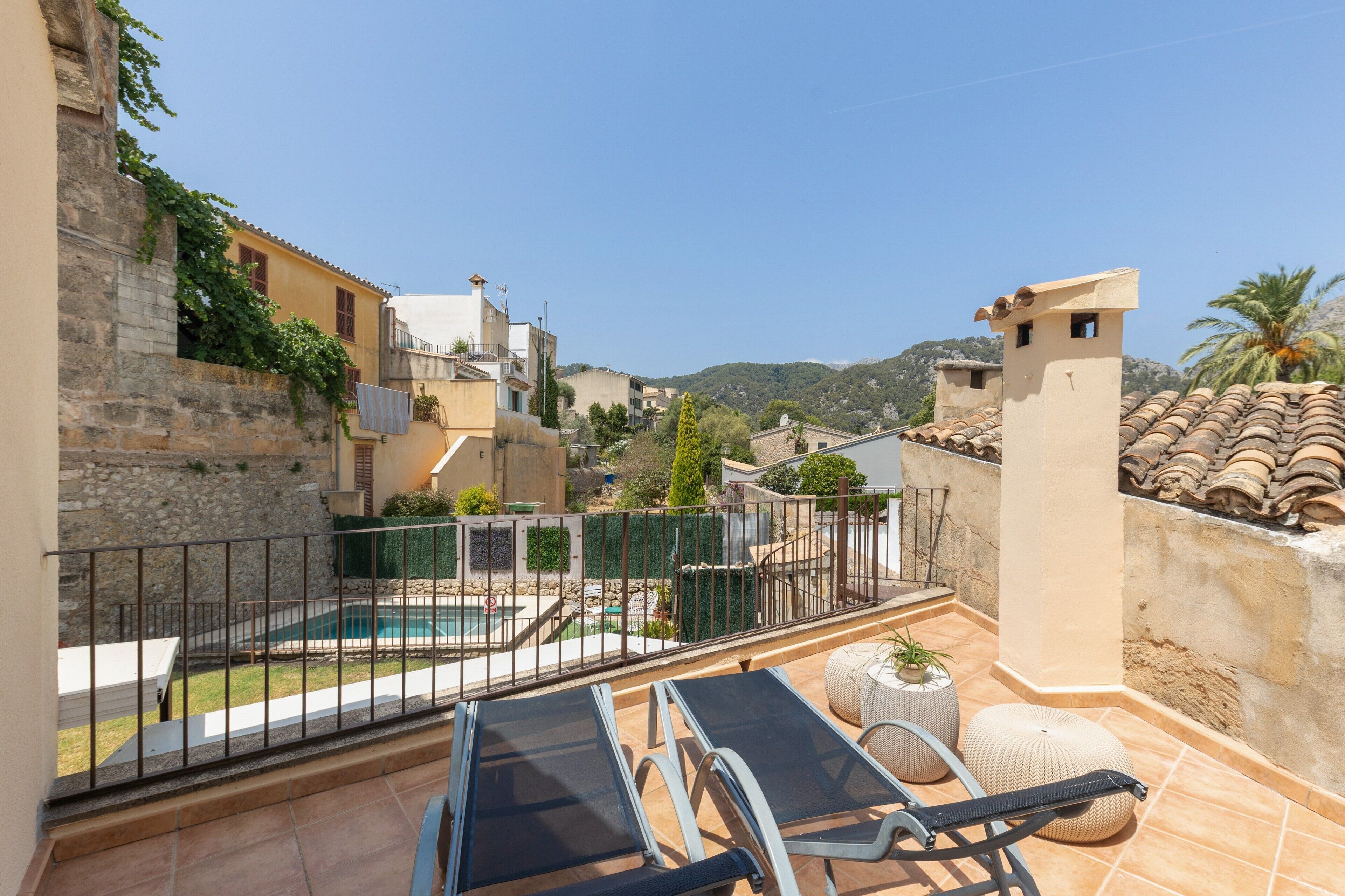 Terraza en la azotea con piscina, sillas de descanso y vistas de los edificios y colinas circundantes.