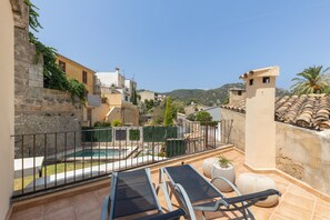 A rooftop terrace with a swimming pool, lounge chairs, and a view of the surrounding buildings and hills.
