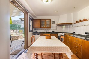 A kitchen with wooden cabinets, a dining table, and a view of the outdoors.