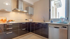 A modern kitchen with black cabinets, a dishwasher, and a window with a view.
