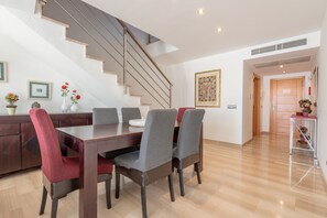 A dining area with a wooden table and chairs, a staircase, and a door leading to another room.