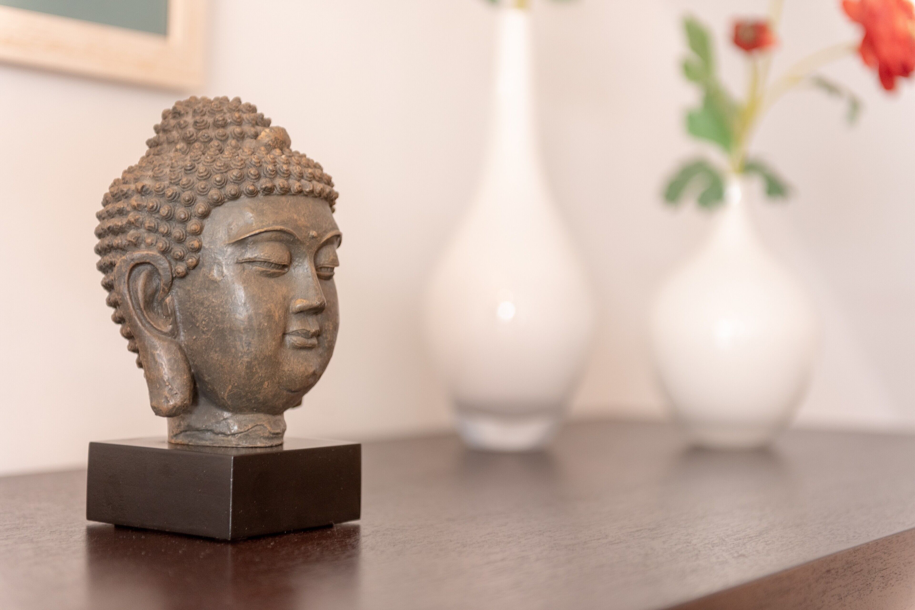 Eine Buddha-Statue auf einem dunklen, quadratischen Sockel.