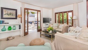 A living room with a sofa, a coffee table, a TV, and a bookshelf. - In perfect location to beach and city - Villa Hibiscus (Pollensa)