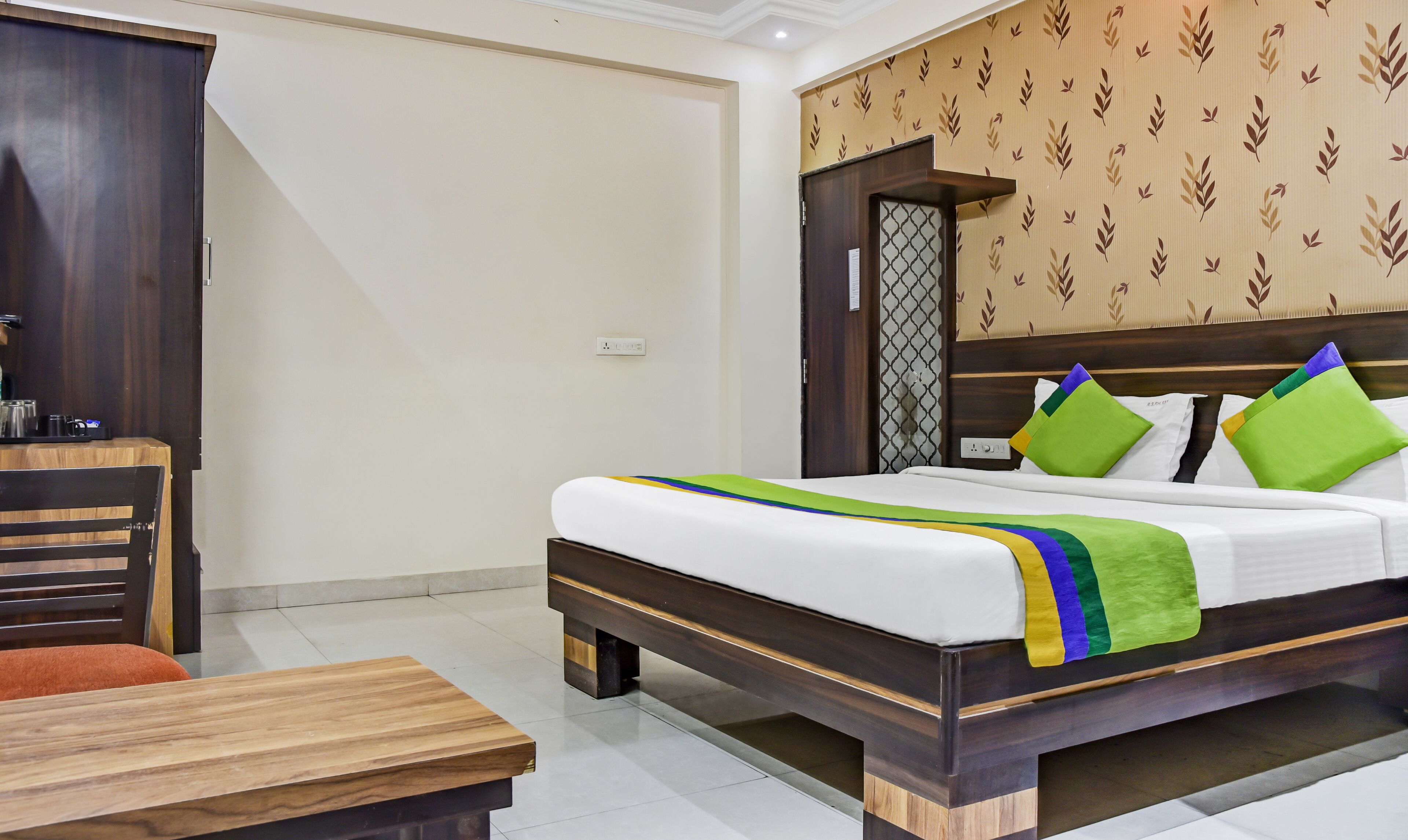 A hotel room with a bed, a wooden desk, and a wardrobe.
