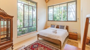 A bedroom with a wooden bed, large windows, a nightstand, and a traditional wooden cabinet. - Unique Country House In Central Israel (Hefer Valley)
