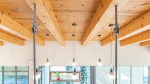 A room with wooden ceiling beams, hanging pendant lights, and large windows with a view of greenery outside. - Unique Country House In Central Israel (Hefer Valley)