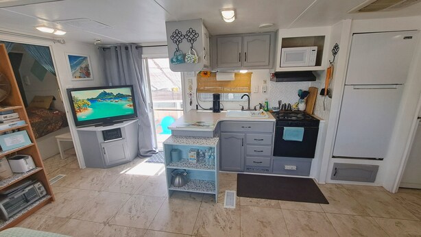 Una cocina compacta equipada con televisión, lavamanos, estufa y refrigerador.