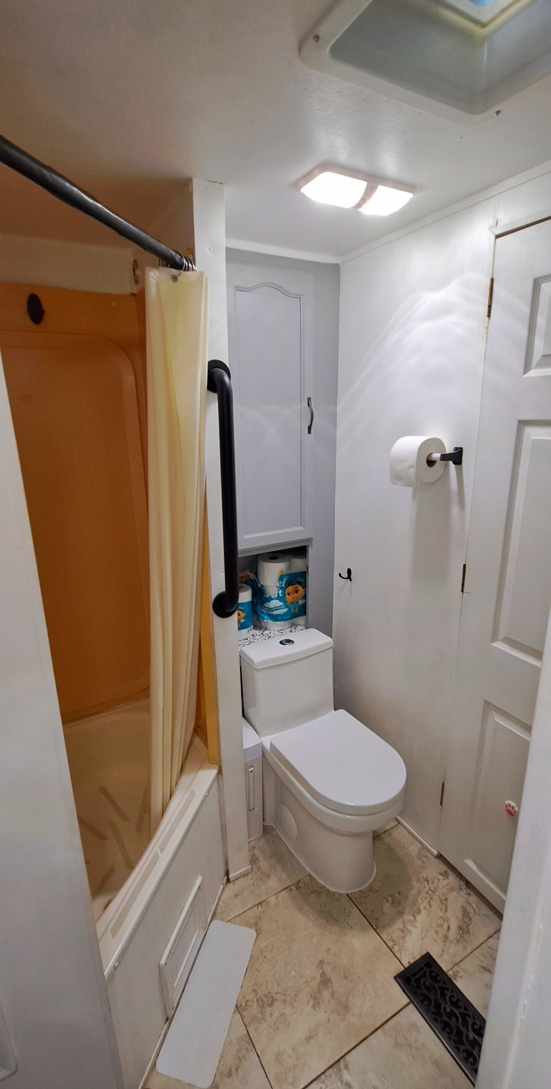 A compact bathroom with a shower, toilet, and sink.