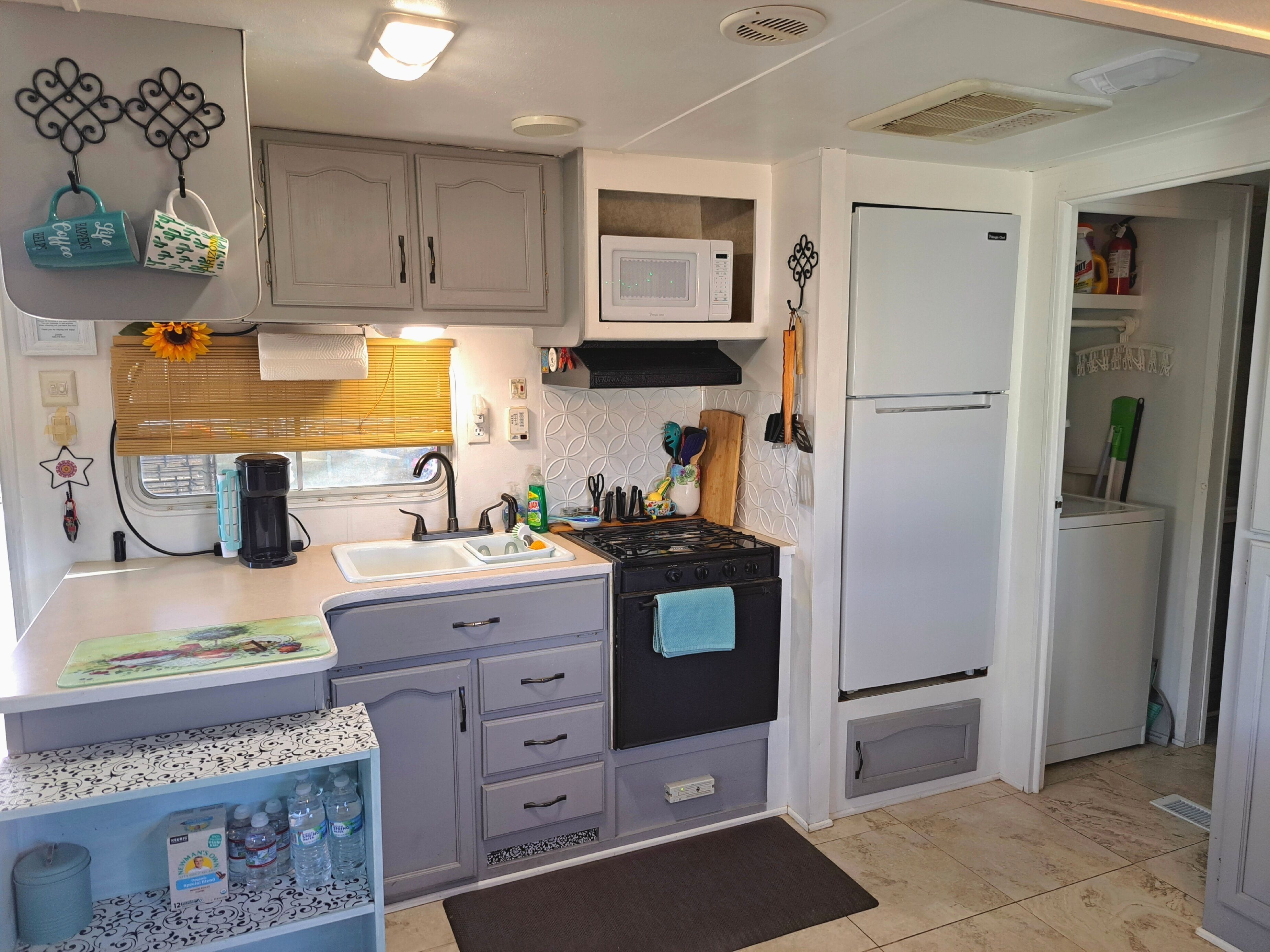 A compact kitchen with a sink, stove, microwave, and refrigerator.