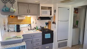 Cocina compacta con lavamanos, estufa, microondas y refrigerador.