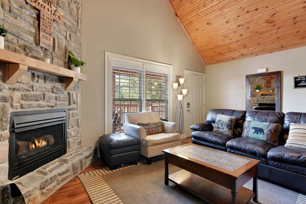 A cozy living room with a stone fireplace, leather sofas, and a wooden ceiling. - Dog-Friendly Cabin Near Silver Dollar City, Onsite Golf Course & Free Tickets (Reeds Spring)