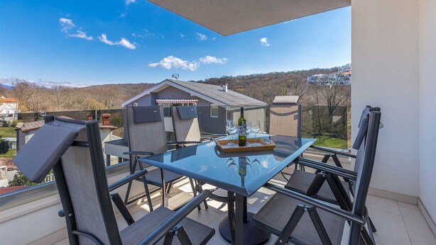 A balcony with a glass table, chairs, and a bottle of wine. - Apartment LAGANINI III (Njivice)