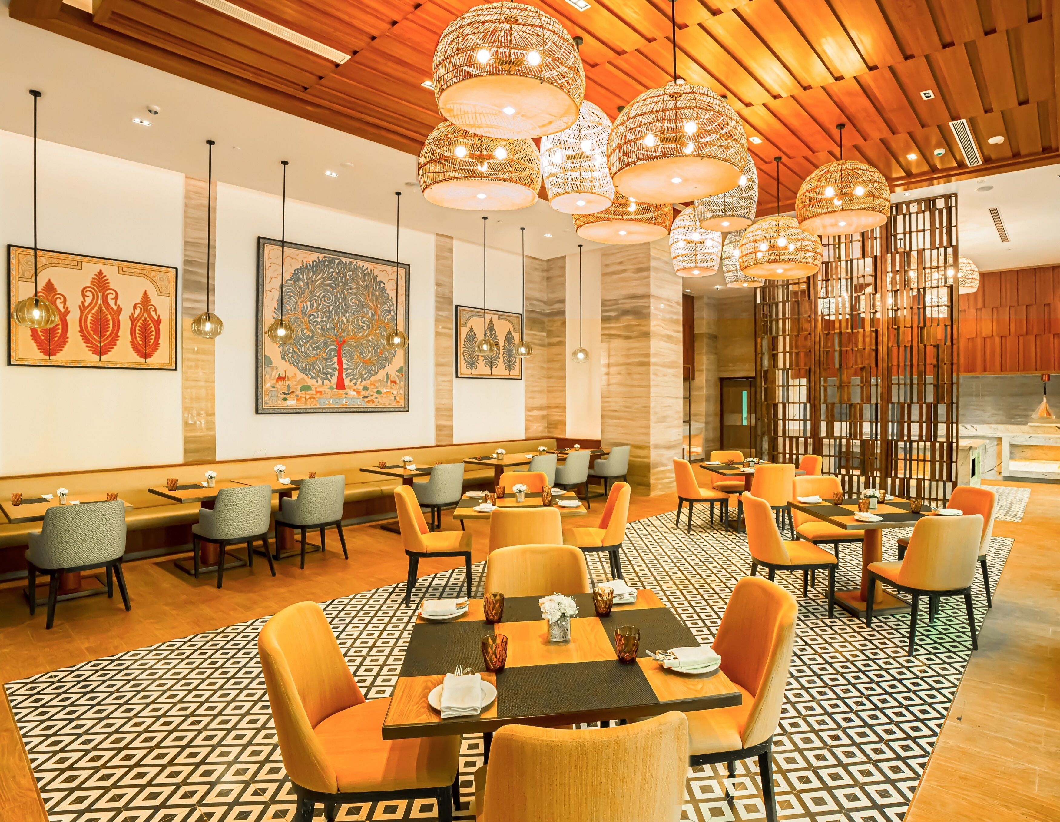 A restaurant with wooden ceiling, hanging wicker chandeliers, and patterned floor tiles.