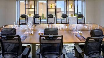 A conference room with a long table, chairs, and decorative shelves with vases.