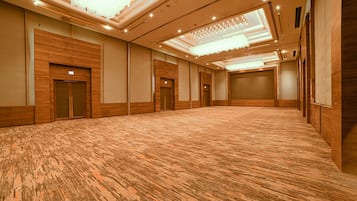 A spacious conference room with a patterned carpet, wooden paneling, and multiple doors.