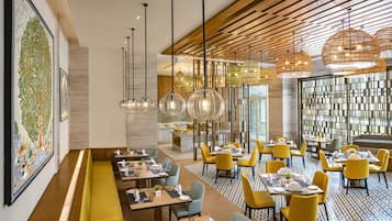 Un restaurante moderno con techos altos, vigas de madera y diversas opciones de asientos, incluyendo mesas y cabinas.