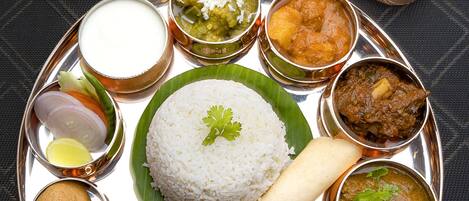 A traditional South Indian meal with rice, curries, and a variety of side dishes on a metal tray.