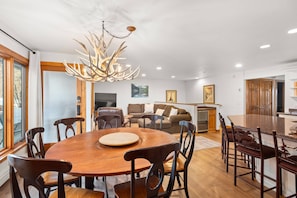 A modern kitchen with a large island, wooden dining table, and chairs.