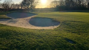 Ein Golfplatz mit Sandbunkern und blauem Himmel.