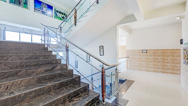 A modern interior with a marble staircase, glass railings, and a wooden wall panel. - Treebo Atithi Comforts, 1 Km From Nisargadhama Forest (Somvarpet)
