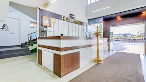 A reception desk with a sign, a staircase, and a carpeted area. - Treebo Atithi Comforts, 1 Km From Nisargadhama Forest (Somvarpet)