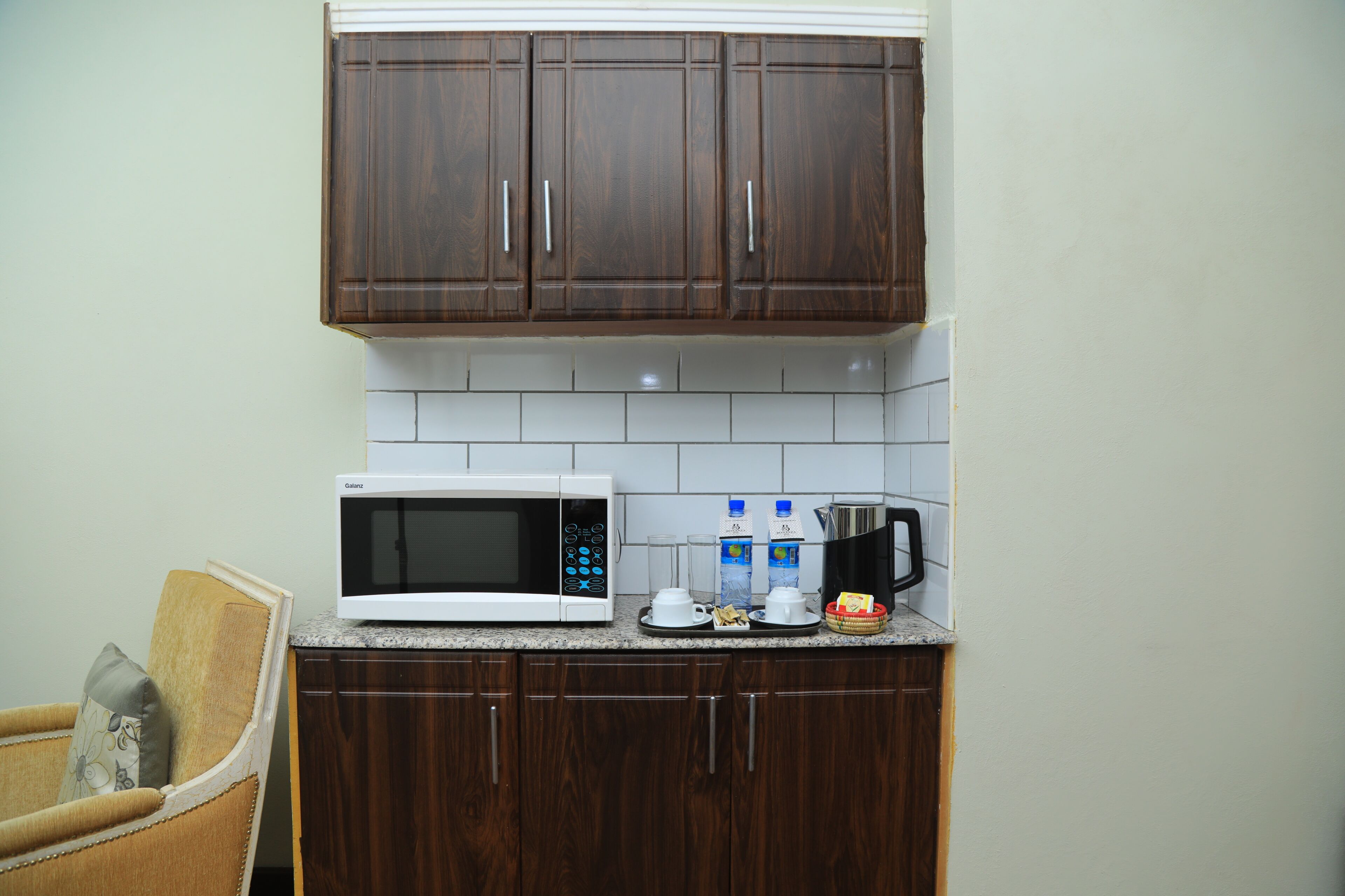 A kitchen with dark wooden cabinets, a white microwave, and a coffee maker on the counter.