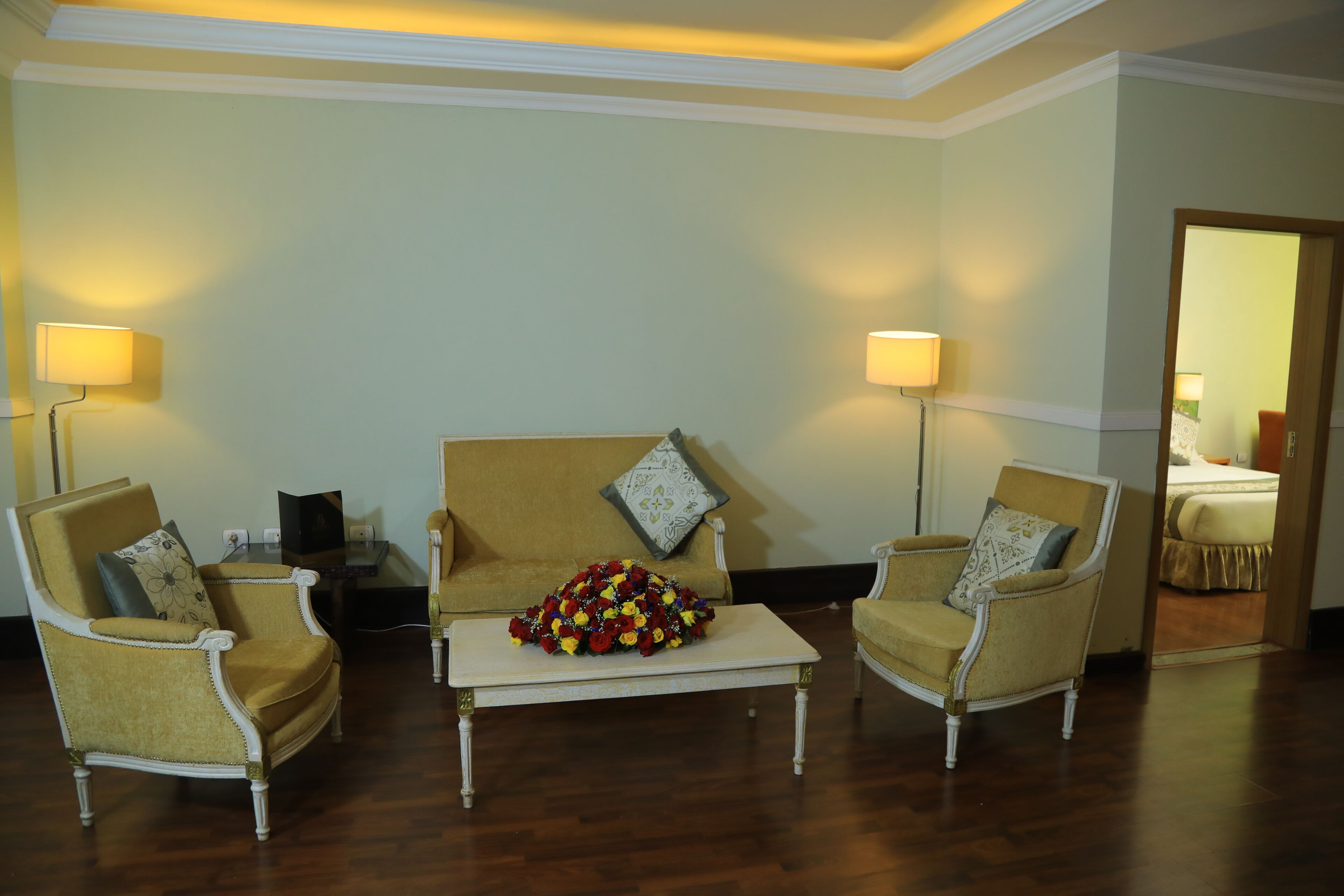 A room with a sofa, two armchairs, a coffee table, and lamps.
