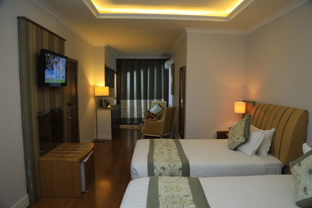 A hotel room with two beds, a television, a desk, and a chair.