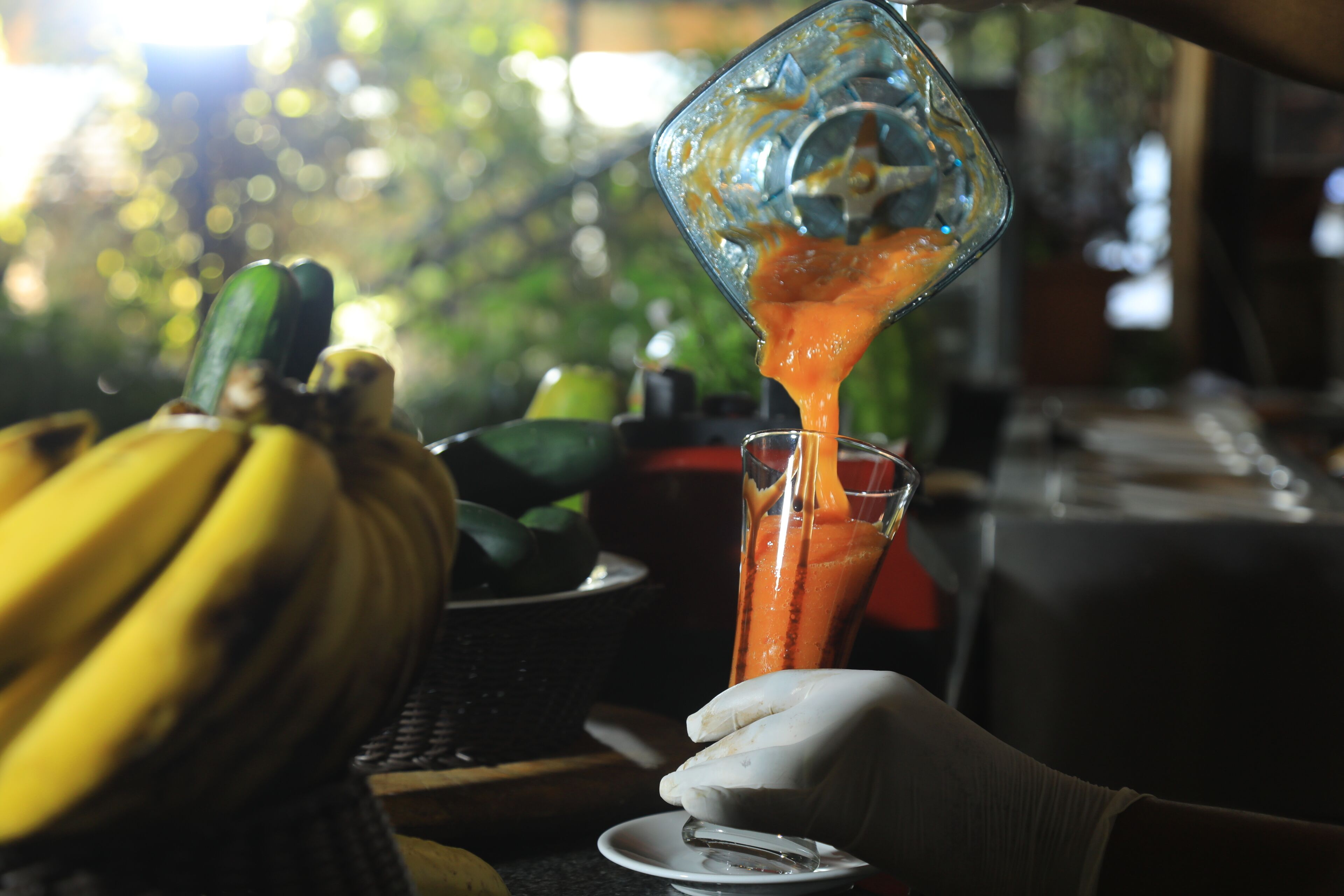 Iemand giet een vloeistof uit een blender in een glas.