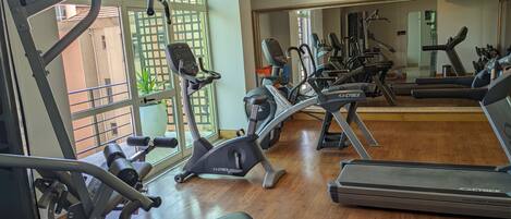 A gym with various exercise equipment including treadmills, stationary bikes, and elliptical machines.