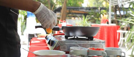 A person preparing food outdoors with a portable stove, bowls, and eggs on a table.