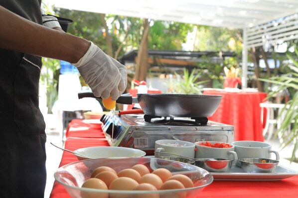 A person preparing food outdoors with a portable stove, bowls, and eggs on a table.