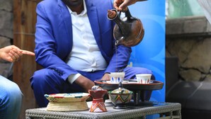 A man in a blue suit pouring a drink from a traditional vessel. - Bonanza Addis Hotel (Addis Ababa)