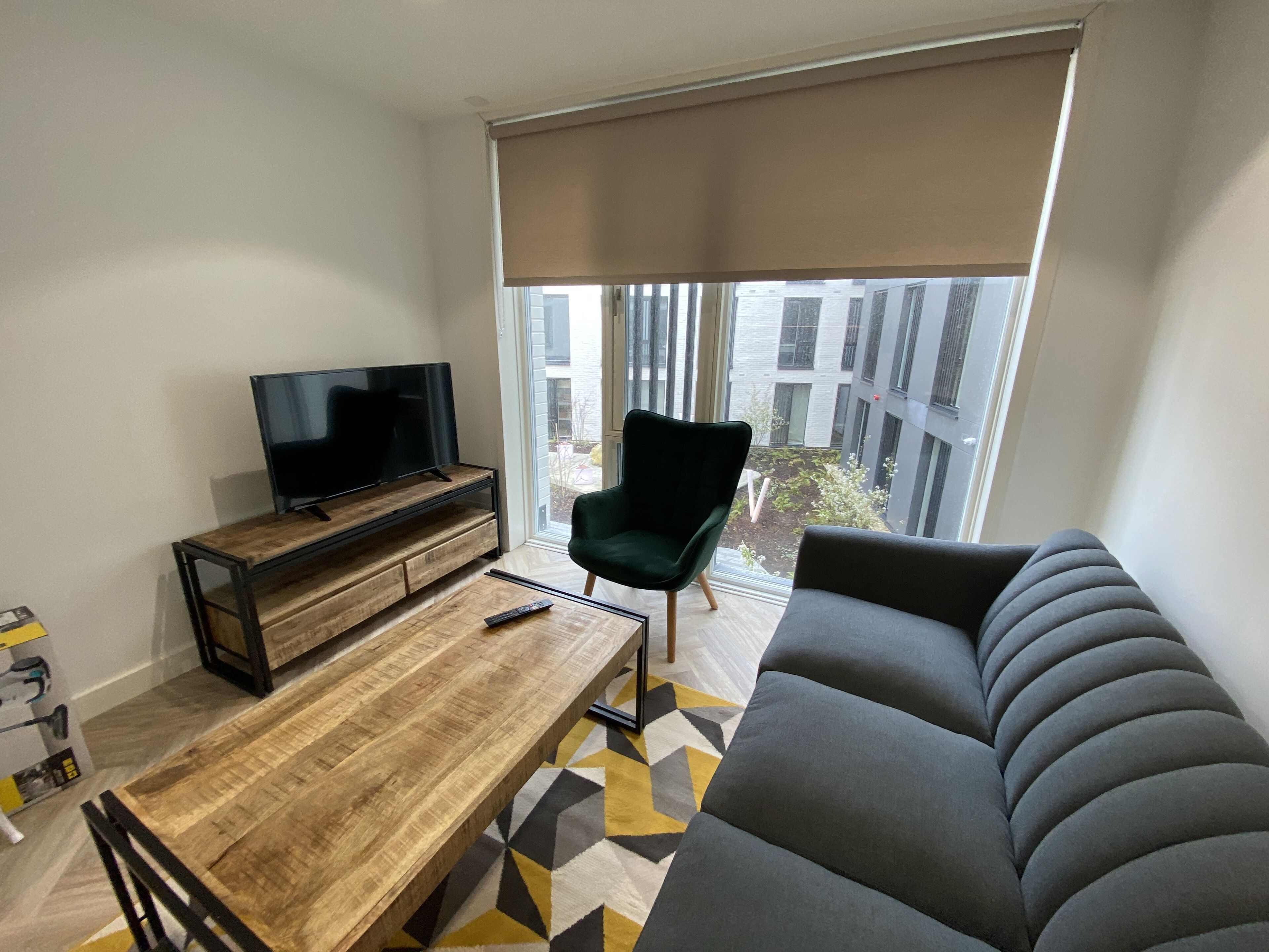 Ein modernes Wohnzimmer mit einer Couch, einem Fernseher auf einem Holzboden, einem Esstisch und einem Stuhl.