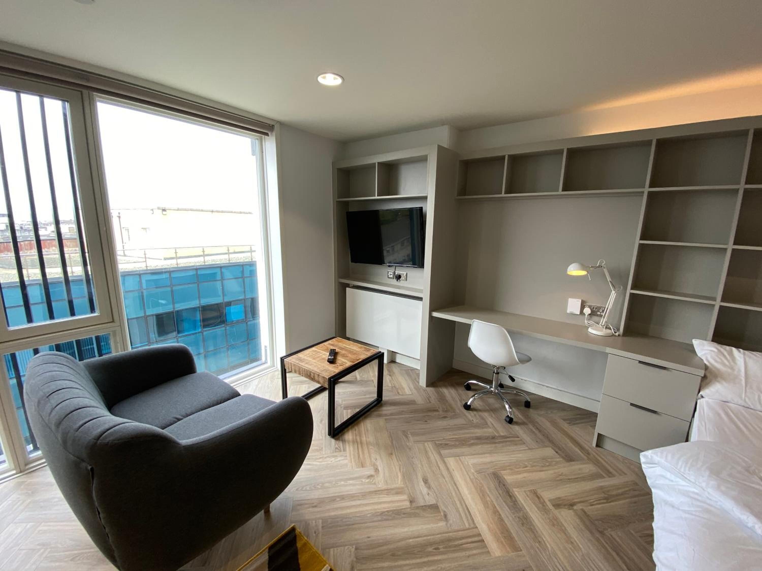 A modern living room with a sofa, a coffee table, a TV, and a desk with a chair.