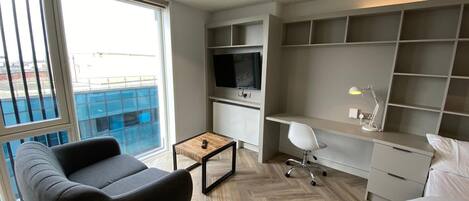 A modern living room with a sofa, a coffee table, a TV, and a desk with a chair.