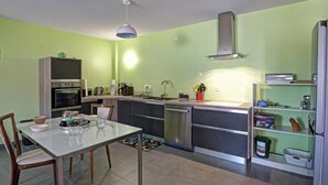 A compact kitchen with a dining table, chairs, an oven, a sink, and a built-in stove. - Modern Apartment with Balcony and Fiber Internet in Saint-Genest-Malifaux (Saint-Genest-Malifaux)