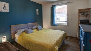 A bedroom with a bed, a bedside table, a window with curtains, and a wardrobe. - Modern Apartment with Balcony and Fiber Internet in Saint-Genest-Malifaux (Saint-Genest-Malifaux)