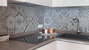 Una cucina con piastrelle decorative sul backsplash, un piano di lavoro nero, un lavello e un vassoio con tazze e una scatola con la scritta 'Tea'.