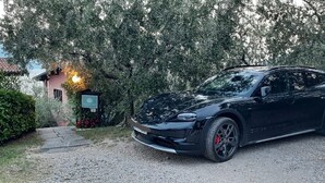 Un SUV nero parcheggiato in un vialetto, sullo sfondo una casa e degli alberi.