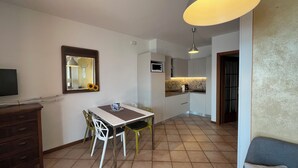 Un ambiente compatto con angolo ristoro, angolo cottura e divano.