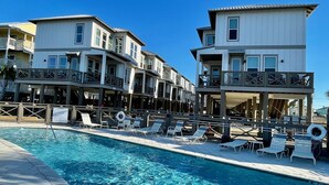 Ein Hotel am Wasserufer mit Pool, mehreren Balkonen und Liegestühlen.